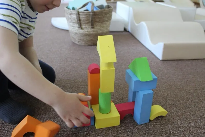 Dijete slaže šarene drvene kocke u igraonici